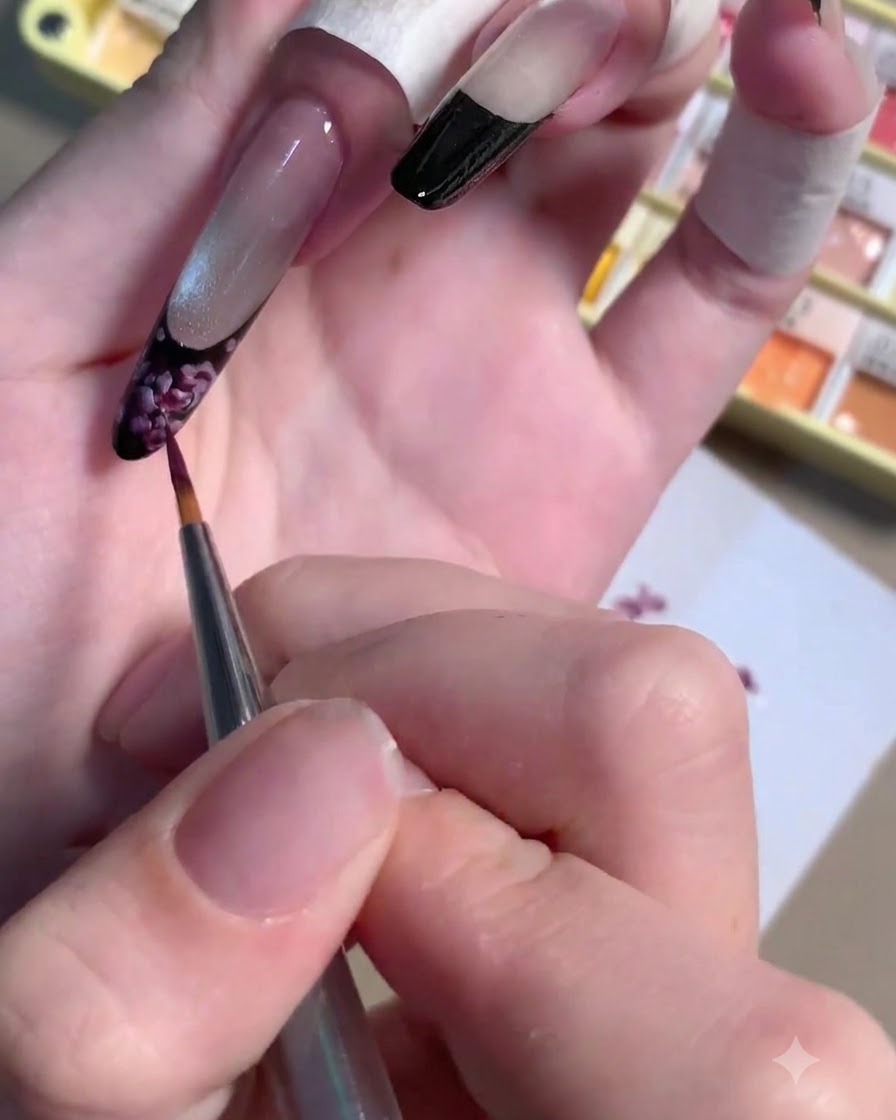 Un pincel delineador delgado aplicando un pequeño punto de gel ciruela oscuro en el centro de una rosa pintada.