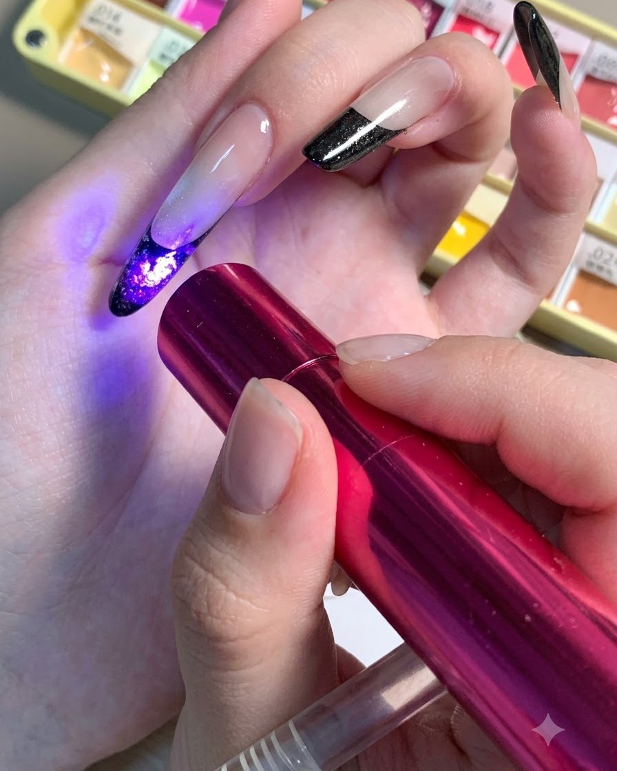 Una mini lámpara UV/LED roja sostenida sobre una uña para curar los detalles oscuros del centro de un diseño floral.