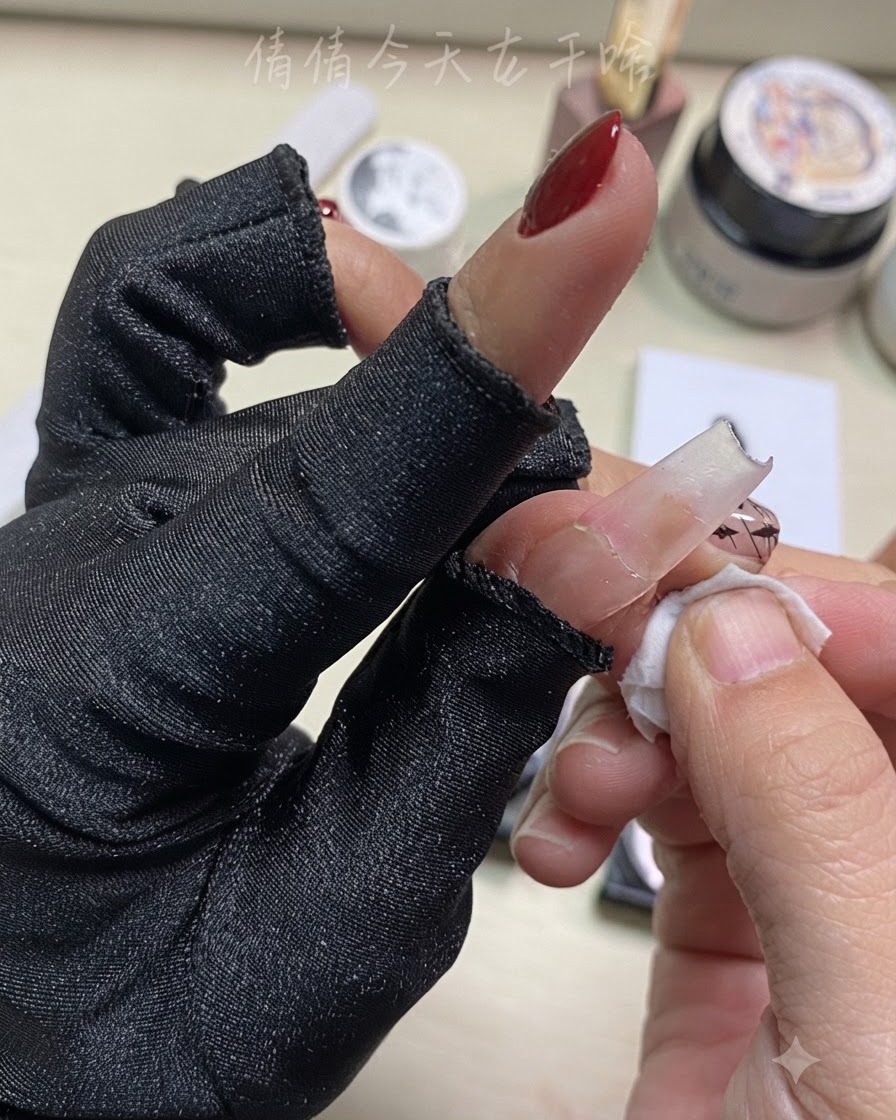Primer plano de una mano limpiando un dedo con un disco limpiador cerca del nail art preparado.