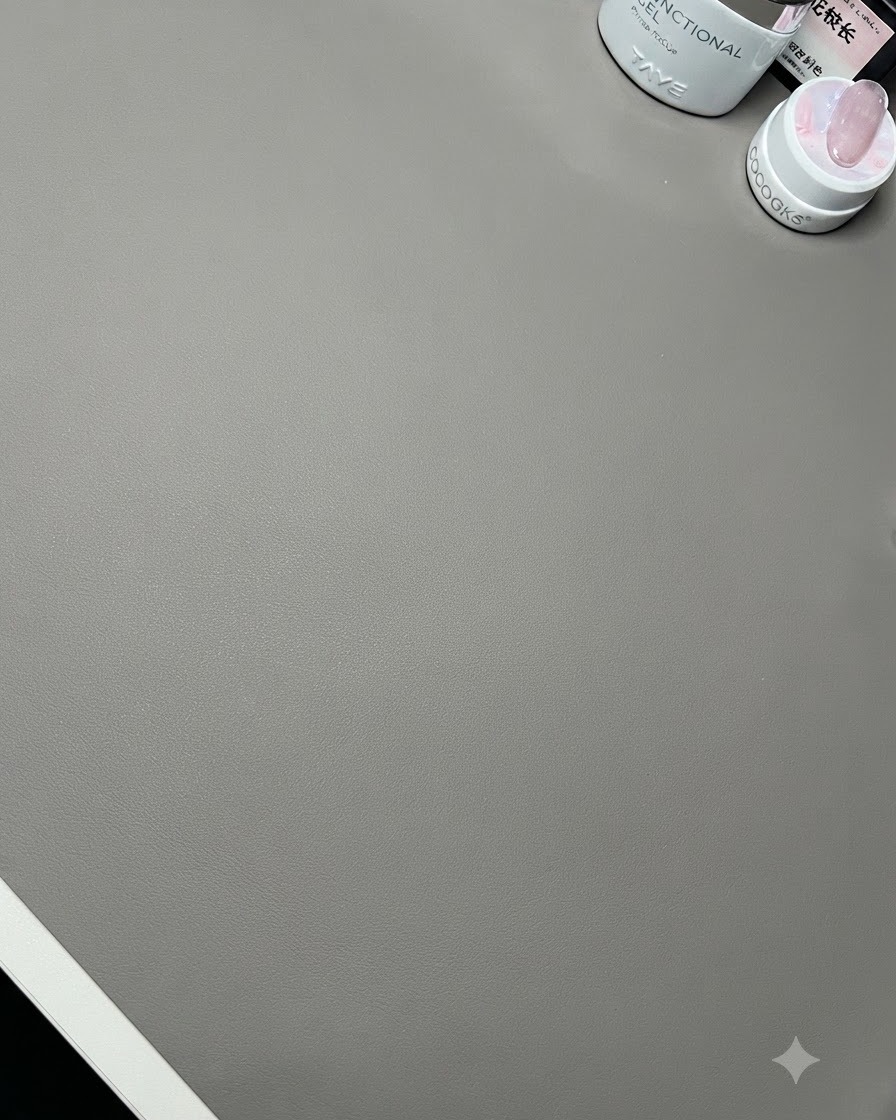 Una vista de cerca de una superficie de escritorio limpia con botellas de preparación de uñas y un soporte de exhibición de madera.
