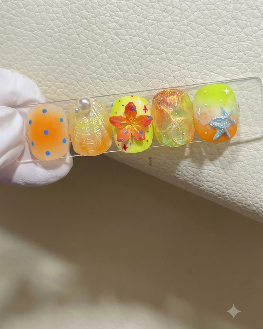 Una mano con guantes sosteniendo un soporte de exhibición de uñas que muestra cinco diseños de uñas coloridos de temática veraniega.