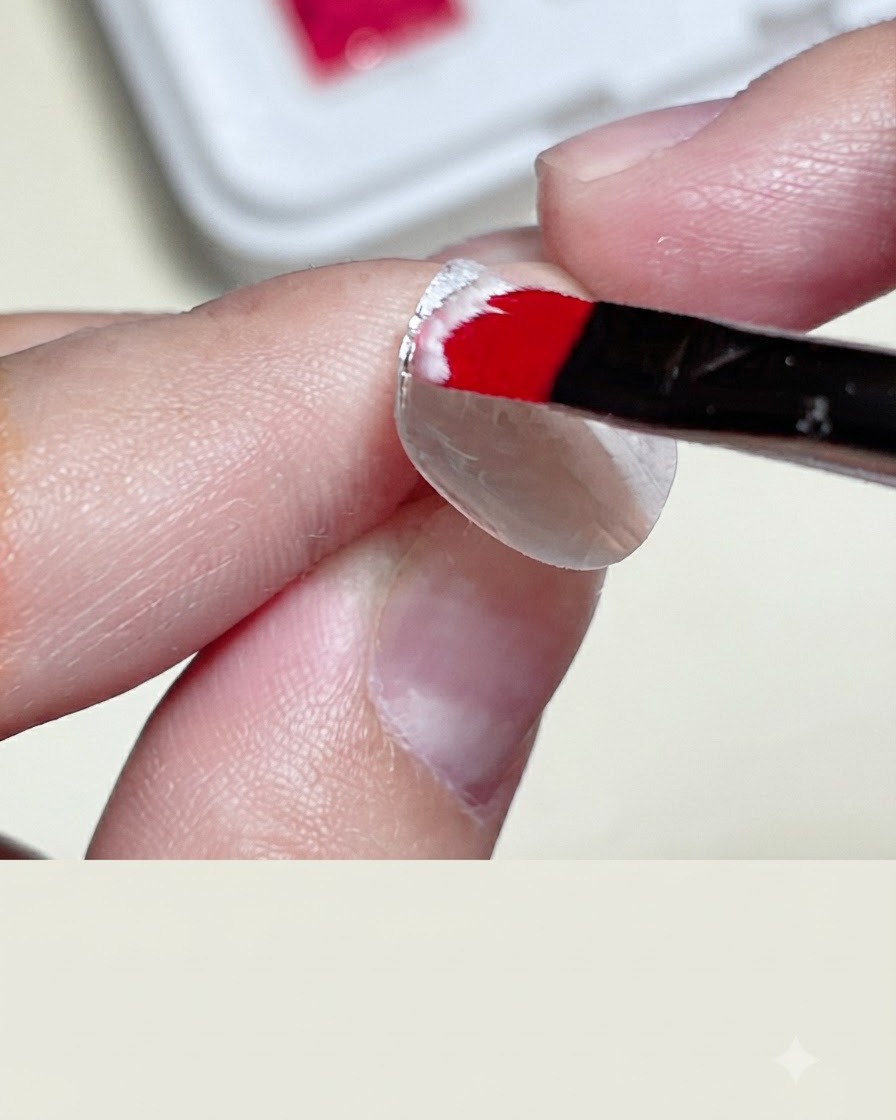 Un primer plano de una mano aplicando tiras de cinta adhesiva transparente sobre una base de uña blanca para crear un área cuadrada bordeada.