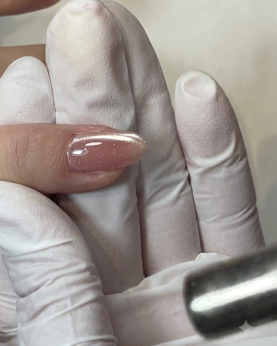 Un pincel plano aplicando una capa transparente de base coat sobre la uña.