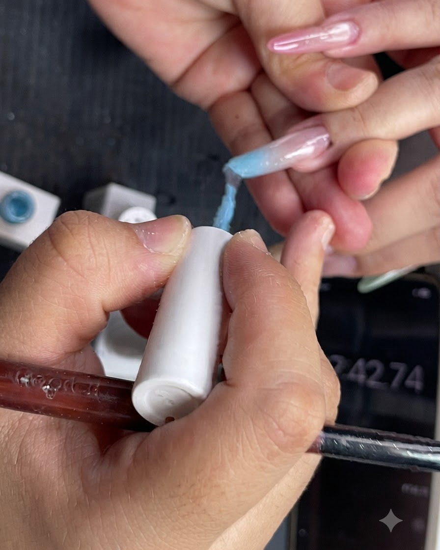 Vista en primer plano de esmalte en gel azul claro siendo aplicado en la mitad superior de una uña.