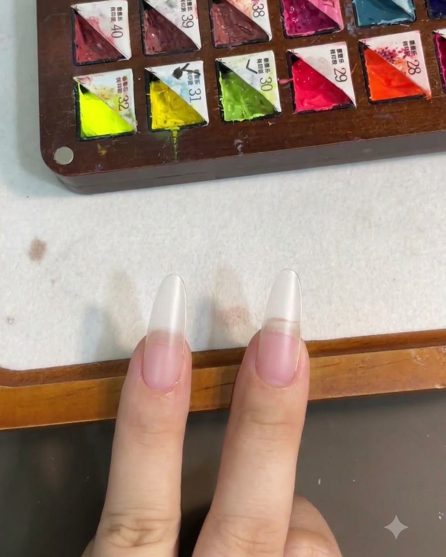 Uñas que se muestran después de curar la capa de gel base bajo una lámpara de uñas.