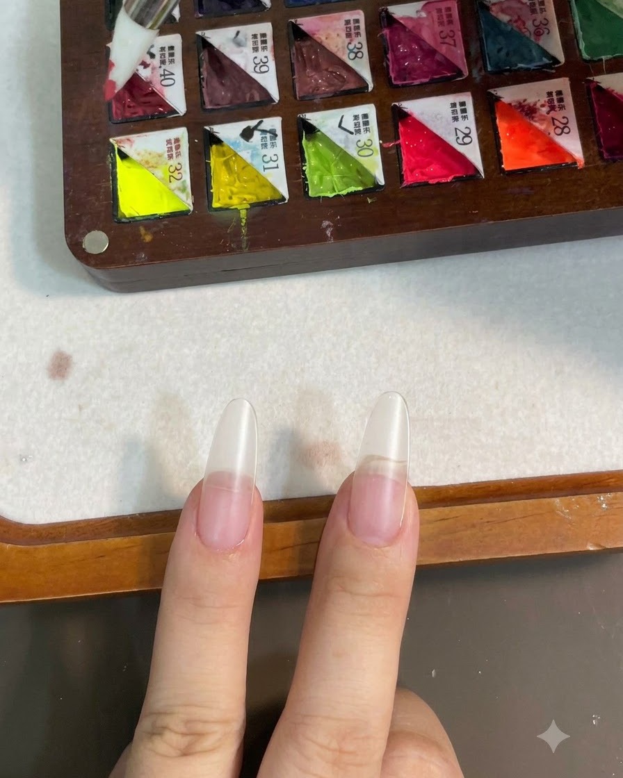 Un pincel de silicona tomando gel de color rosa de una paleta compartimentada.