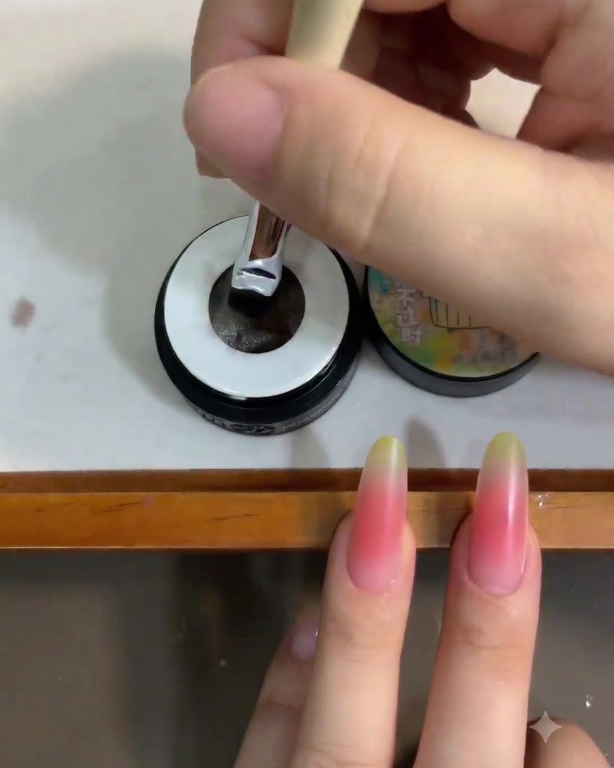Un pincel de uñas sumergiéndose en un pequeño tarro de esmalte en gel ojo de gato blanco translúcido.