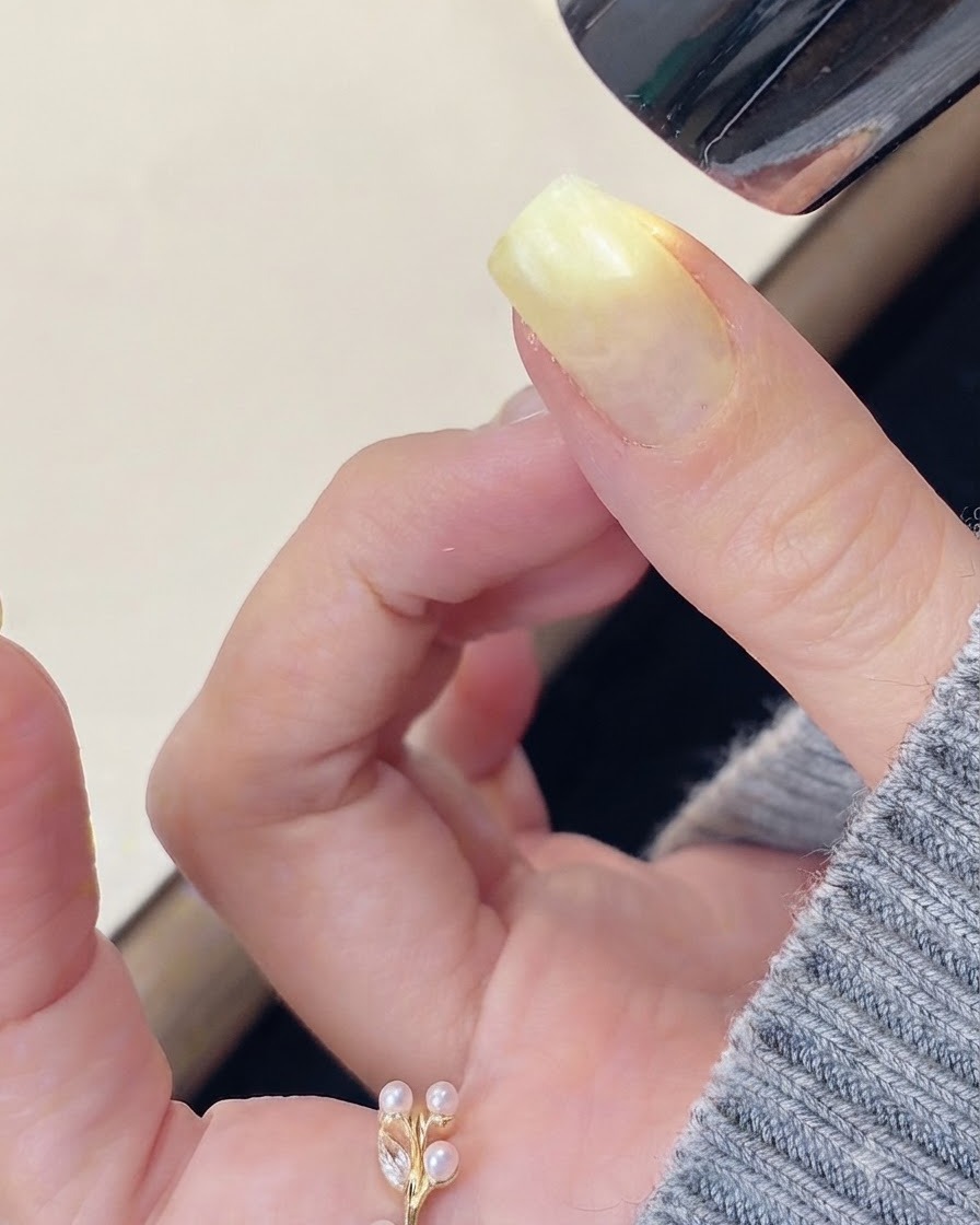 Un pincel aplicando gel de construcción transparente sobre la superficie de una uña preparada.