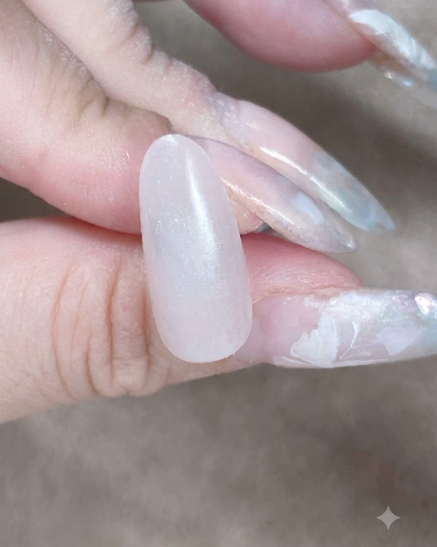 Una vista de cerca de una esponja de maquillaje dando toques a lo largo de la cutícula y el lateral para difuminar una capa base de gel.