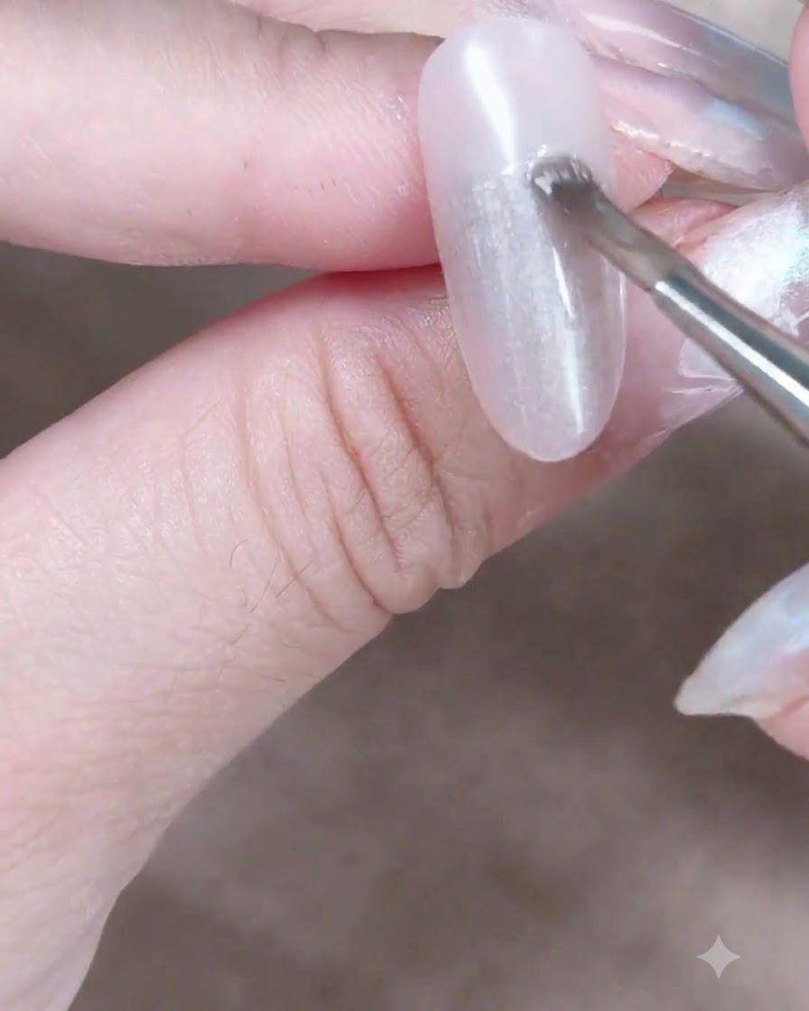 Un imán cilíndrico sostenido cerca de una uña de gel ojo de gato húmeda para atraer y mover las partículas de brillo magnético.