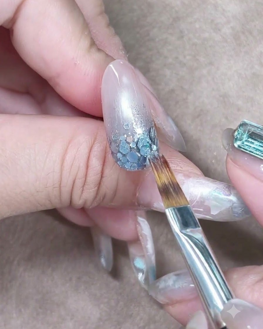 Un pincel acariciando ligeramente el gel azul translúcido hacia abajo para difuminar el degradado de color.