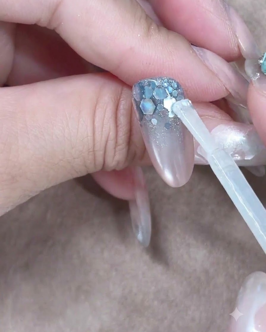 Un pincel de gel constructor colocando una gota transparente cerca de la cutícula para deslizarla por la uña.