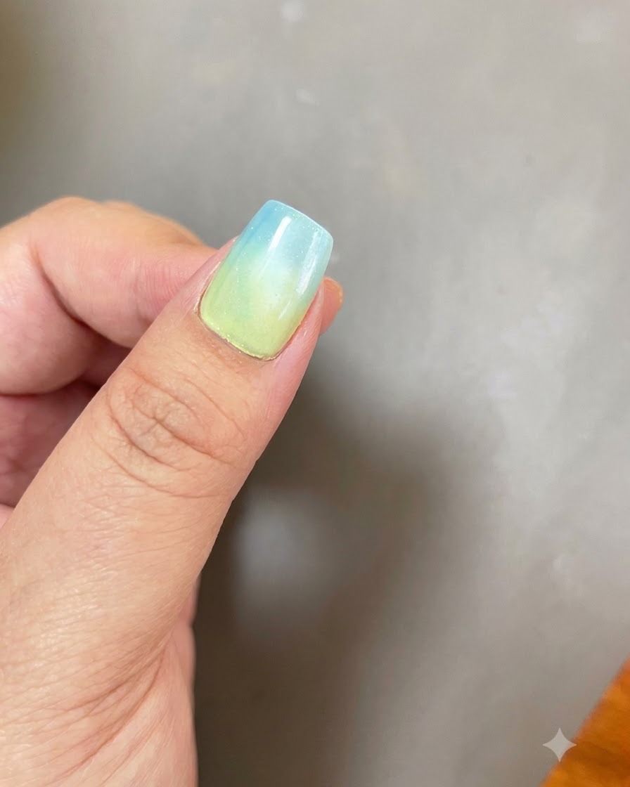 Una uña con una base ombre de azul a amarillo y un efecto de luz magnética circular de ojo de gato posicionado bajo una lámpara de curado UV/LED púrpura.