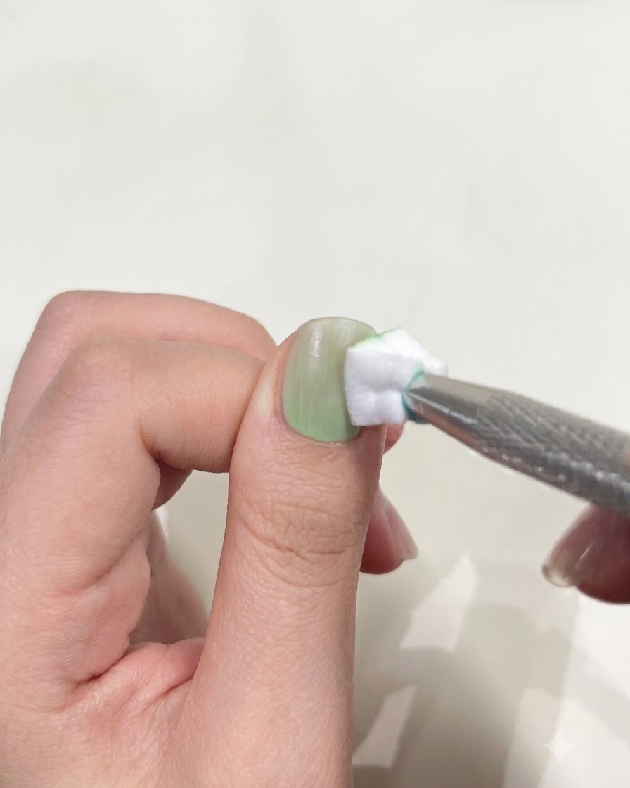Un pulgar posicionado debajo de una mini linterna UV/LED compacta para curar el esmalte en gel.