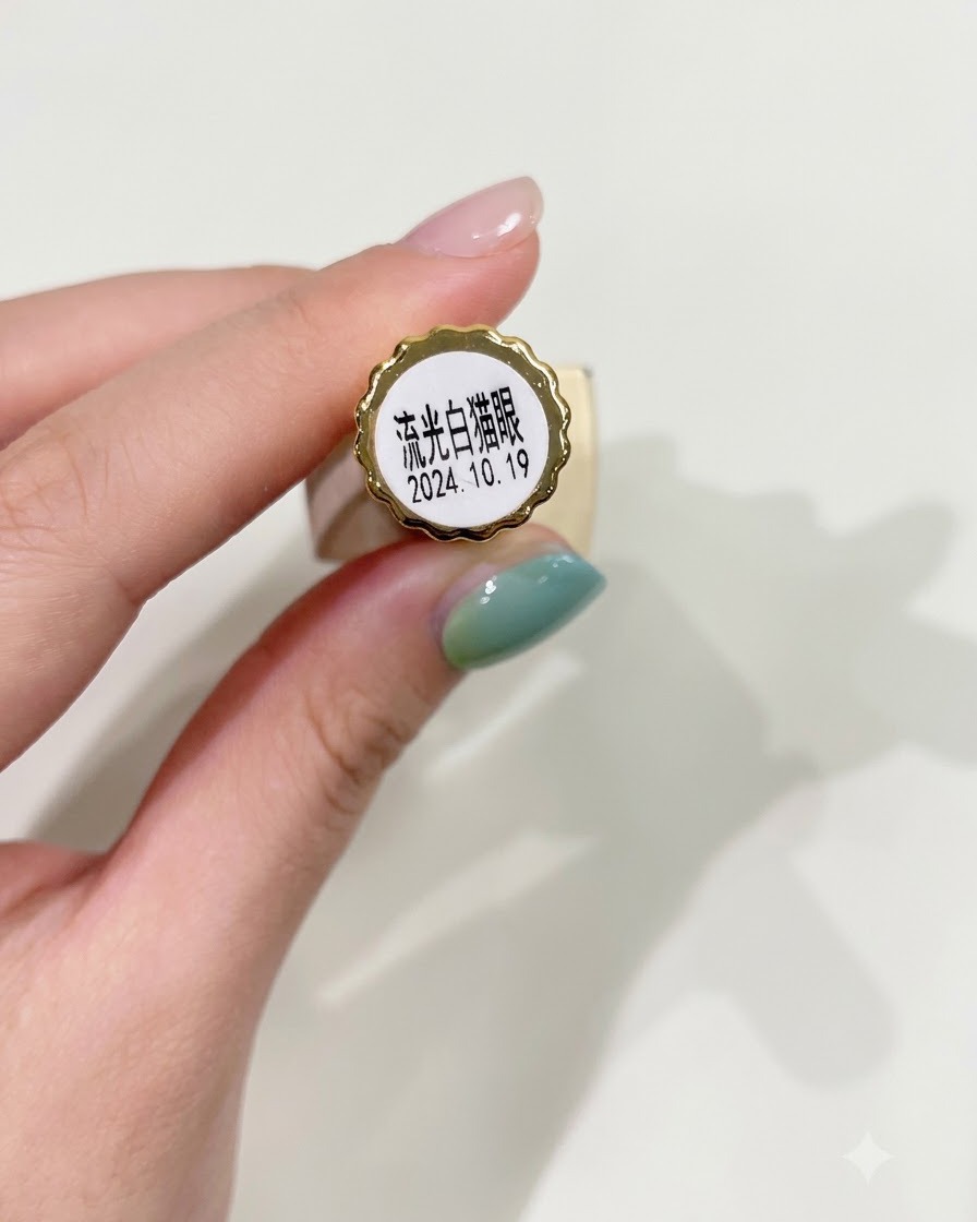 Un pincel de uñas aplicando uniformemente esmalte en gel traslúcido blanco tipo ojo de gato sobre una uña preparada.