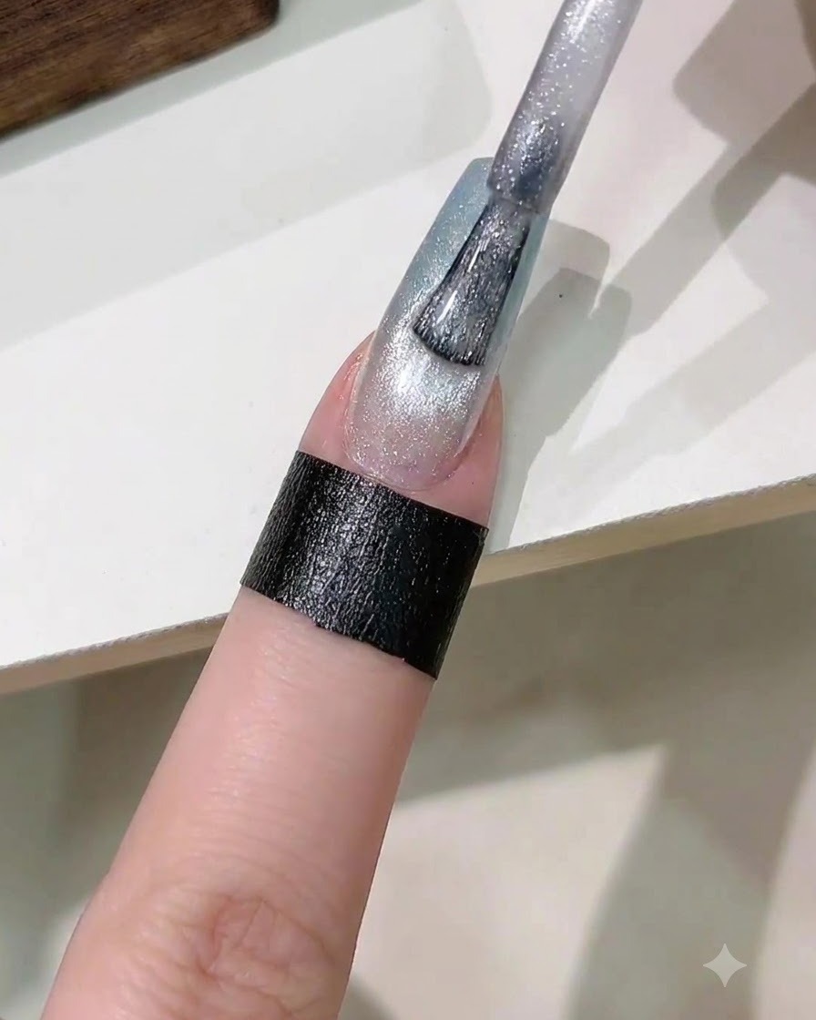 Un pincel aplicando una capa de esmalte en gel magnético ojo de gato plateado sobre la uña degradada.