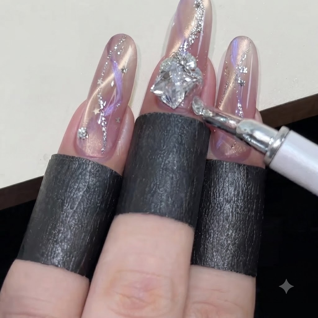 Un lápiz de cera organizando pedrerías redondas pequeñas alrededor de una gema más grande en forma de diamante en una uña de ojo de gato rosa brillante.
