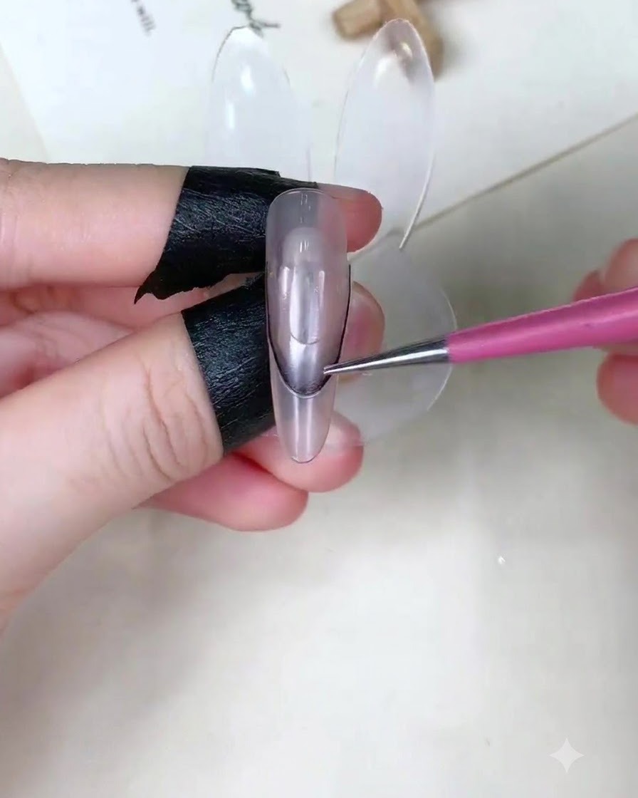 Un primer plano de un dedo sosteniendo una pegatina guía curva en un soporte transparente para exhibición de uñas.