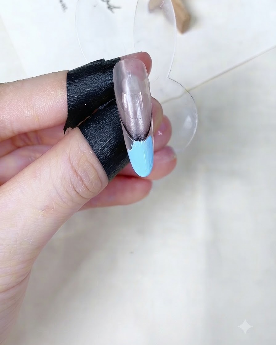 Una esponja de maquillaje dando toques sobre el área de gel azul bebé en un soporte de exhibición de uñas.