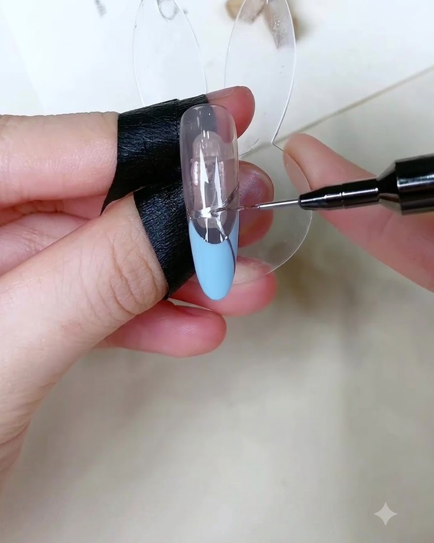 Una herramienta de precisión aplicando diminutos puntos de gel adhesivo transparente sobre la línea plateada de un diseño de manicura francesa.