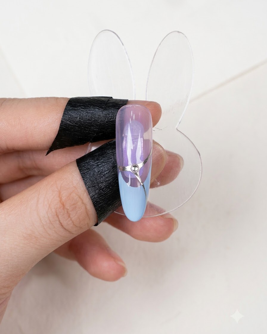 Una exhibición de uñas terminada que muestra un diseño de manicura francesa completado con una línea de acento plateada y un diamante de imitación central.
