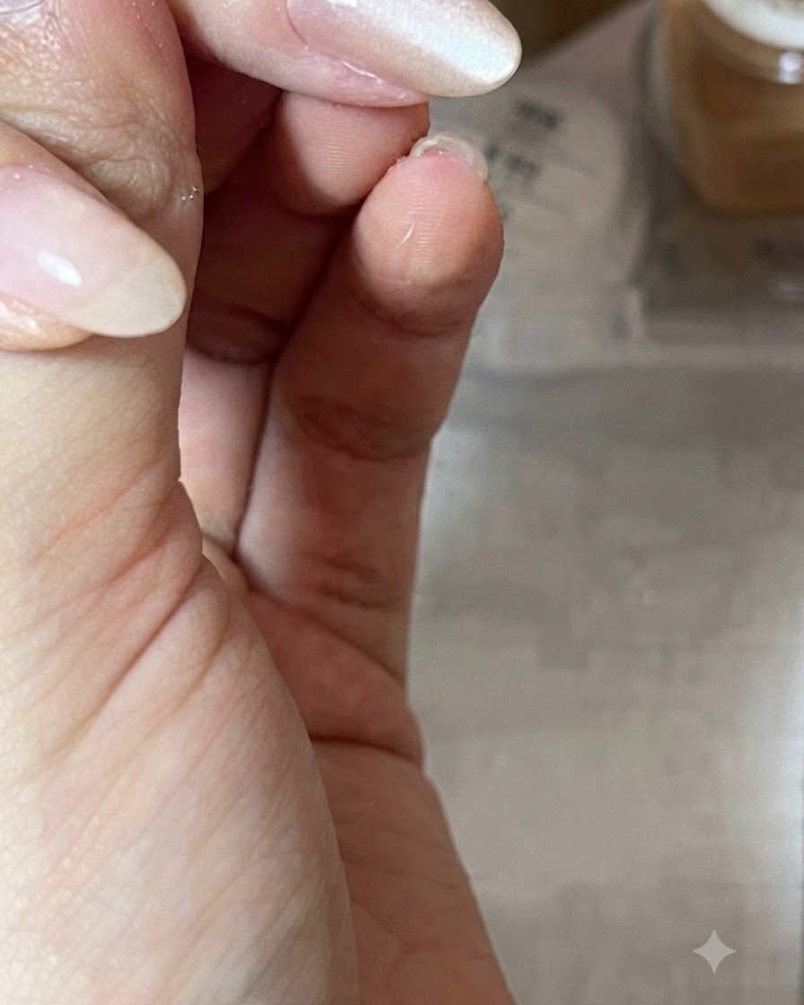 Primer plano de una mano sosteniendo un bastón magnético en diagonal sobre una uña brillante con esmalte gel nude para dar forma al reflejo de luz del ojo de gato.