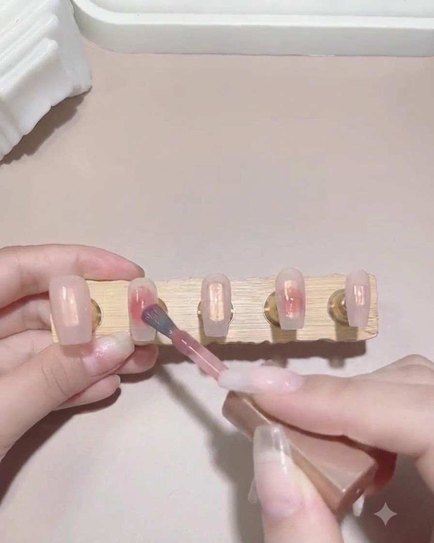 Un pincel aplicando una pequeña gota de esmalte en gel rosa sobre la superficie húmeda de la punta de una uña para comenzar a crear un efecto degradado.