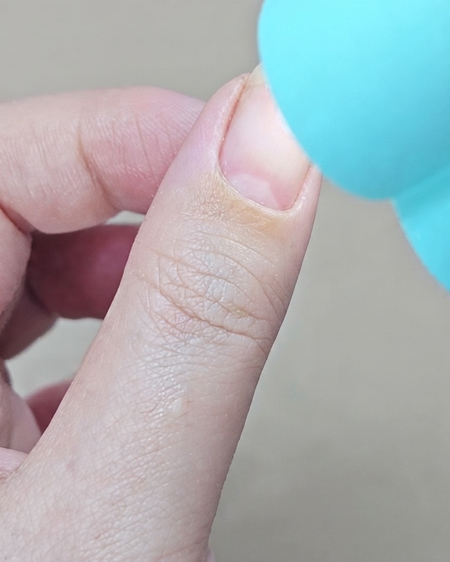 Una lámpara UV azul portátil colocada directamente sobre un dedo para curar la capa de base de gel.