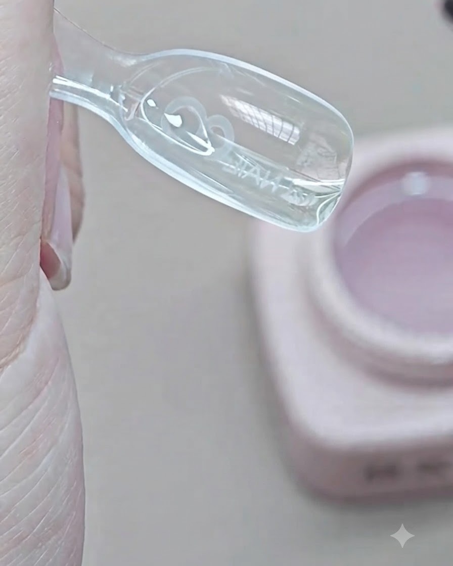 Un pincel colocando gel de extensión transparente en la cavidad interna de un molde dual transparente.