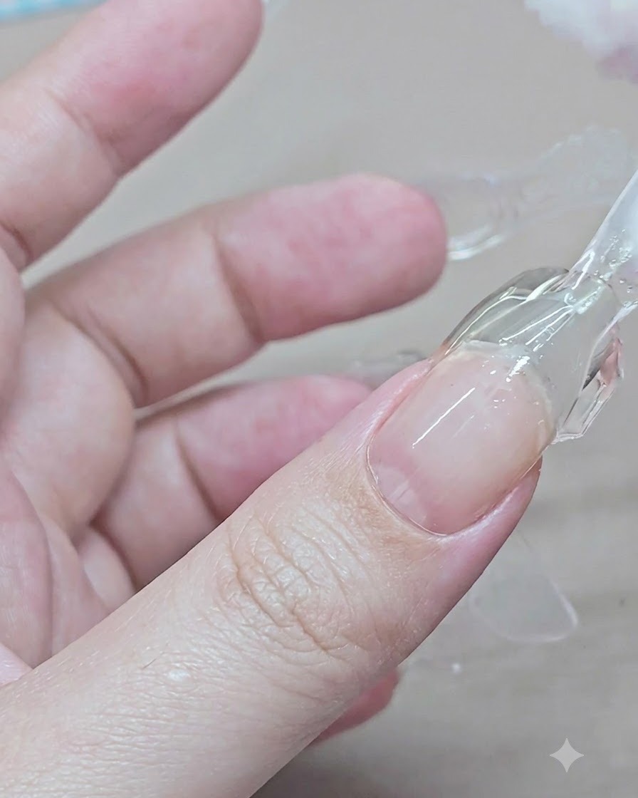 Una mano pellizcando y levantando un molde dual de plástico transparente de una extensión de gel curada en el dedo índice.