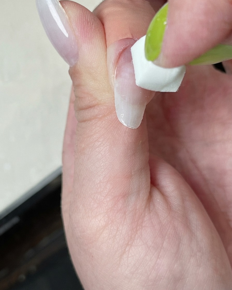 Una uña siendo curada bajo una mini lámpara con un brillo de luz blanca.
