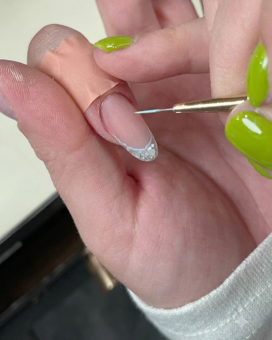 Una uña con una delicada línea de borde azul bajo una mini lámpara LED.