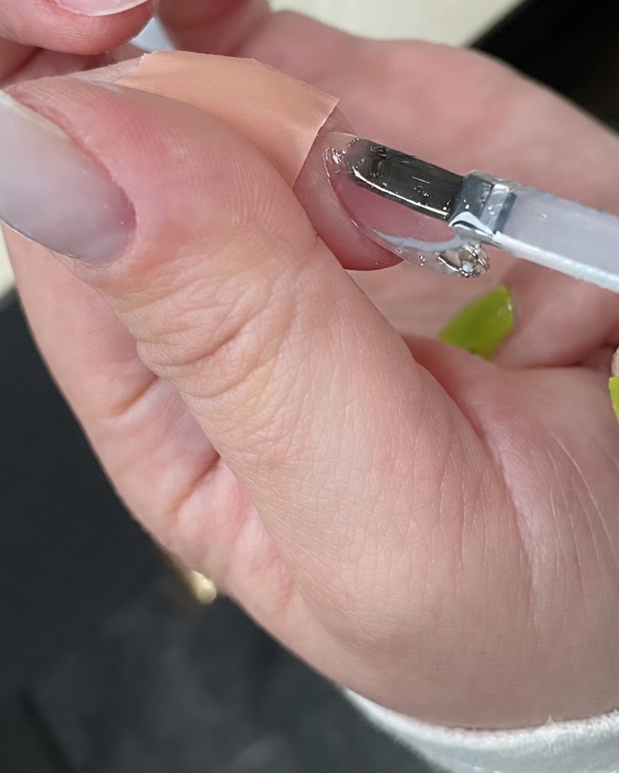 Una mano curando la manicura terminada dentro de una lámpara UV compacta y blanca.