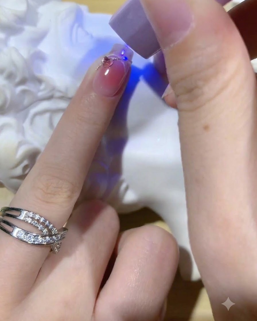 Una lámpara UV morada portátil curando la capa superior brillante final en una manicura blush de ojo de gato terminada.