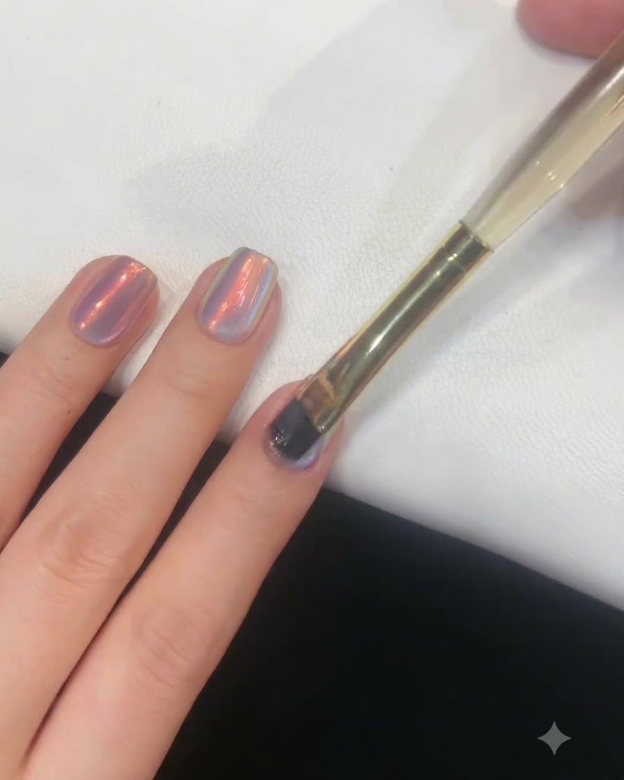 Un pincel para uñas aplicando suavemente una capa fina de gel sobre una uña con acabado aurora.