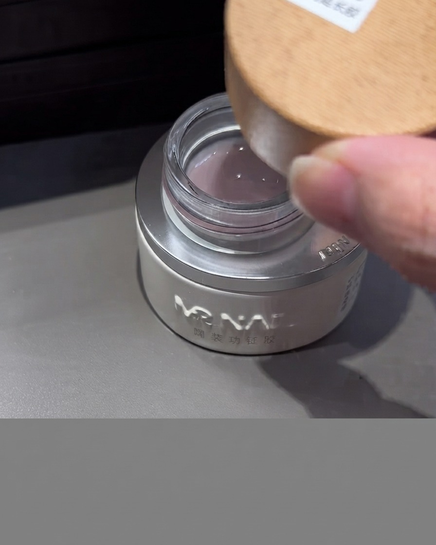 Un frasco de gel de extensión lechoso con tapa de madera abierto, mostrando el gel translúcido lechoso en su interior.