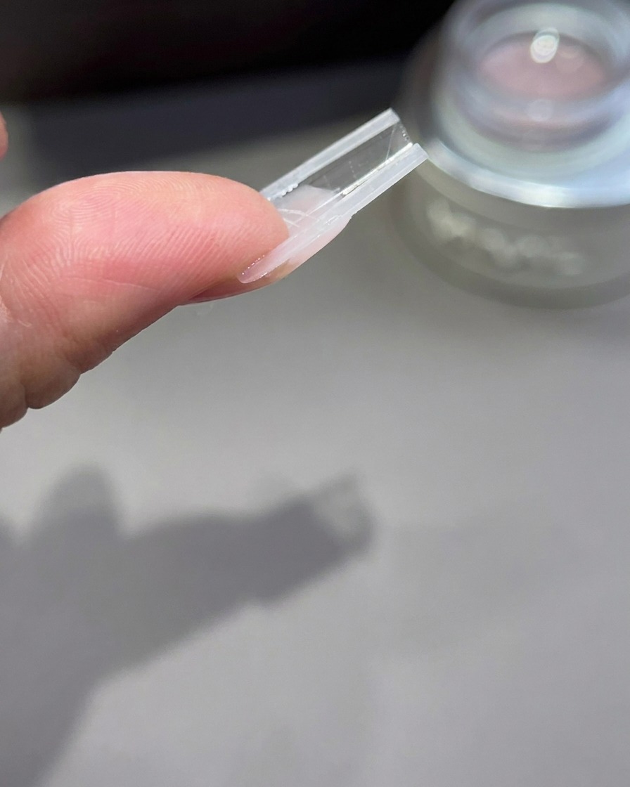 Vista invertida de un molde de extensión de uñas que muestra el perfil y la estructura del arco del gel.