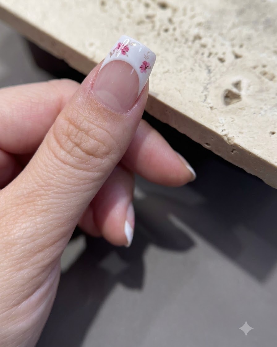 Primer plano de unas pinzas despegando el papel de respaldo de una hoja de pegatinas florales.