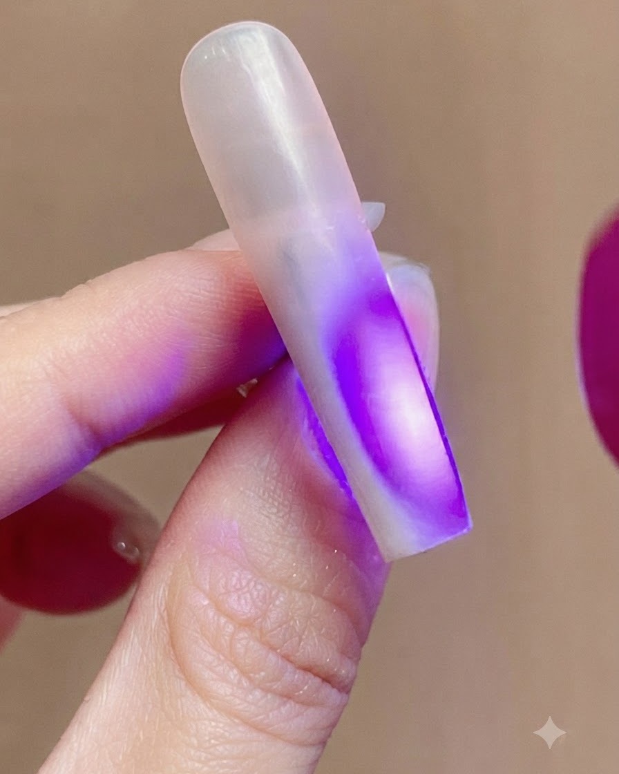 Una uña iluminada por la luz ultravioleta violeta de una lámpara de uñas durante el proceso de curado.