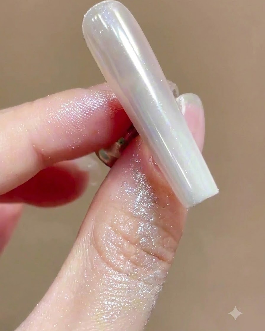 Un pincel suave barriendo el exceso de polvo brillante de una uña con manicura cromo de alto brillo.