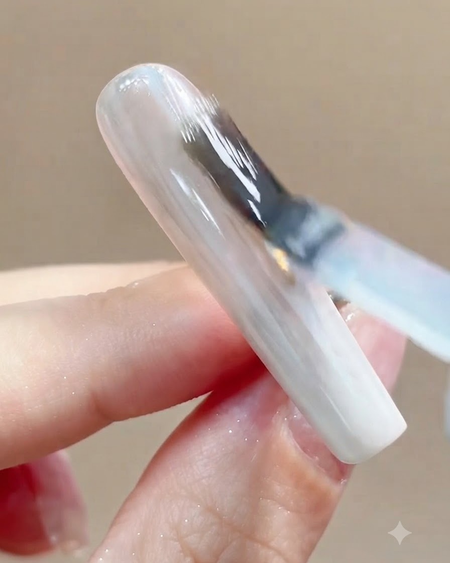 Una vista de cerca de una uña colocándose bajo una lámpara de curado UV o LED después de la aplicación del top coat.