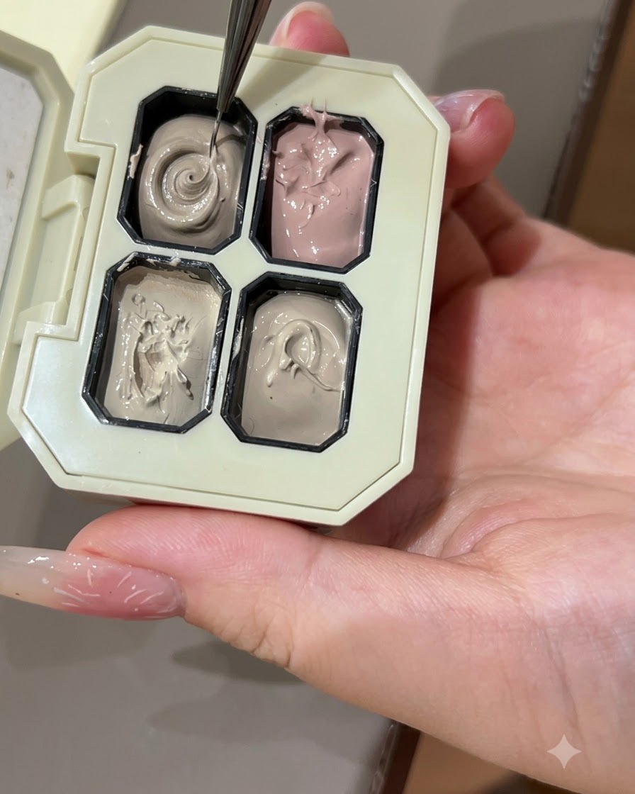 Un pincel de arte de uñas fino tomando gel de color gris de un compartimento en una paleta.