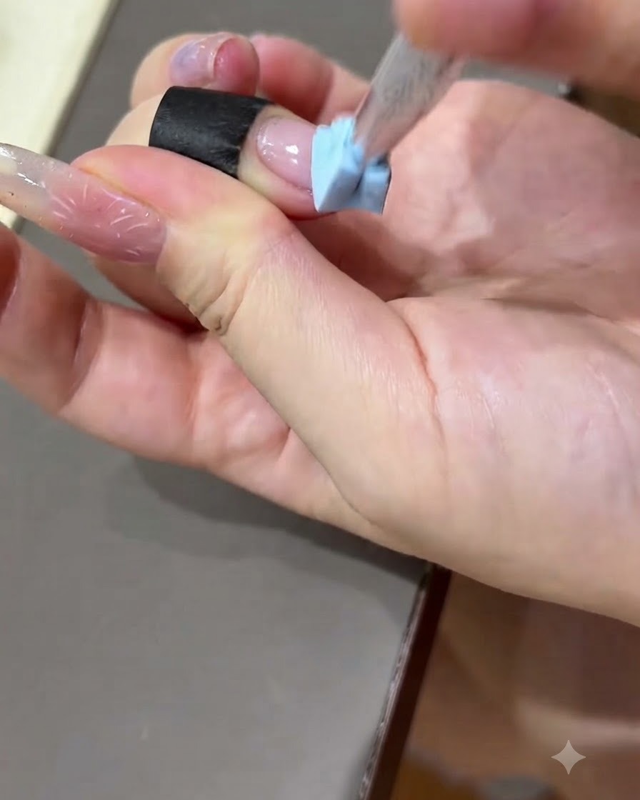 Una mano presionando una tira de práctica negra sobre la superficie de una placa de uñas de práctica.
