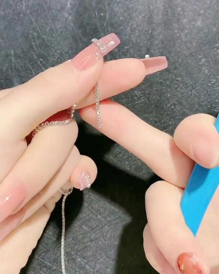Una herramienta colocando una tira de cadena de strass sobre el contorno de gel pegajoso en un dedo.