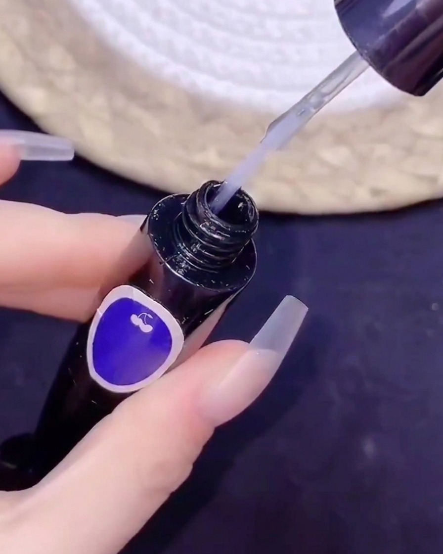 Un pincel fino sumergiéndose en un frasco de top coat sin residuos durante un procedimiento de nail art.