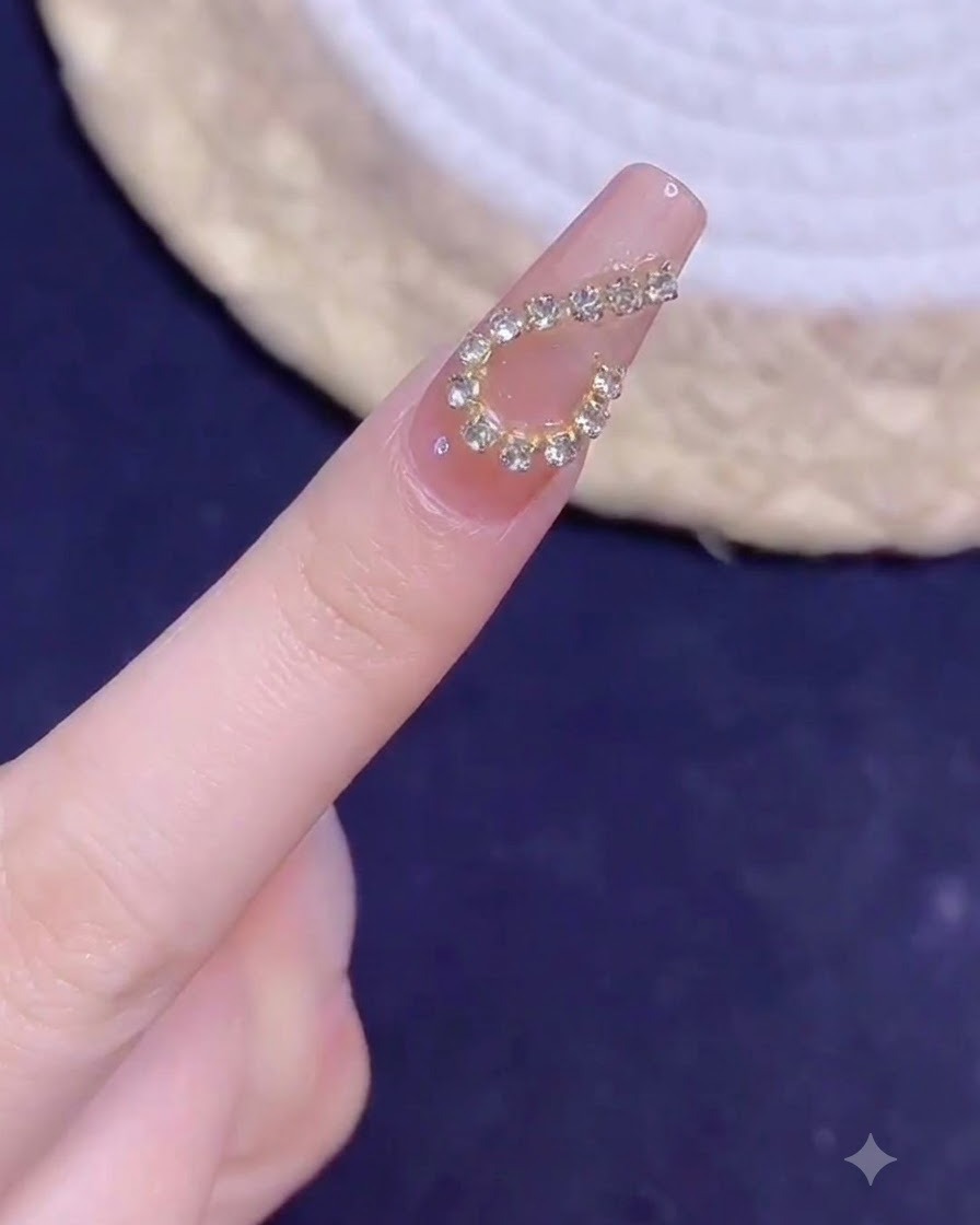 Un dedo manicurado con un diseño de corazón de cadena dorada mostrado en primer plano bajo iluminación después de curar.