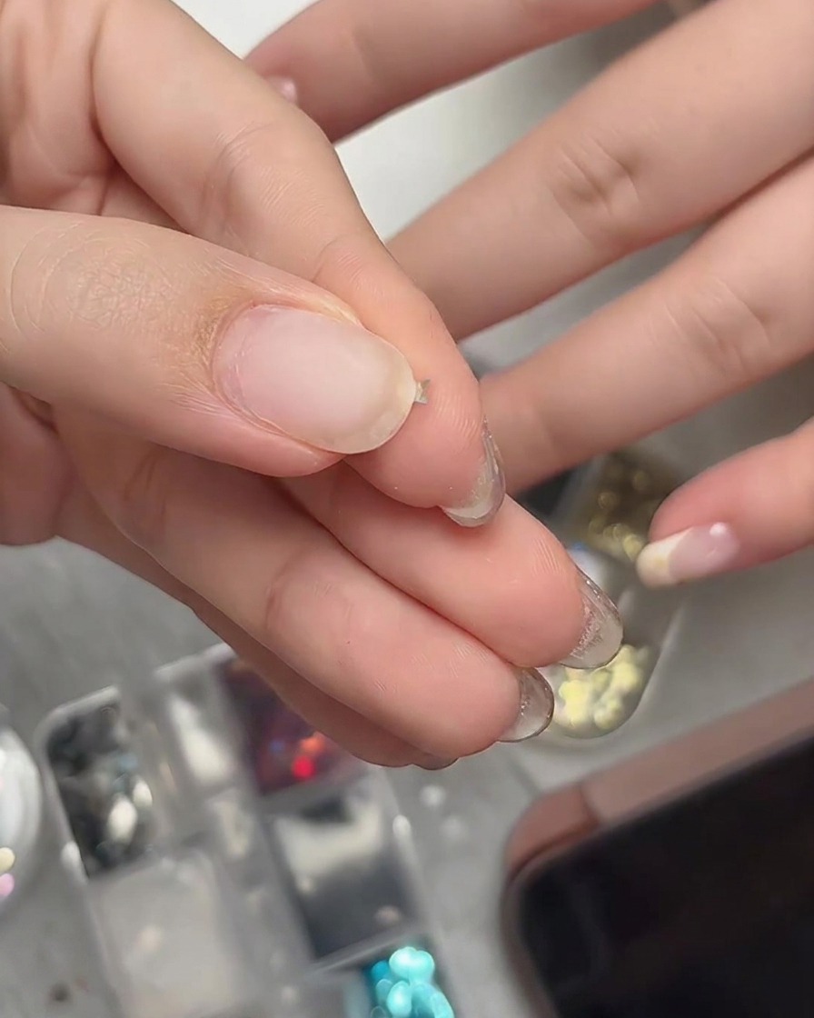 Finger, die ein winziges Stern-Glitzerstück sanft zu einer dreidimensionalen Kurve biegen.