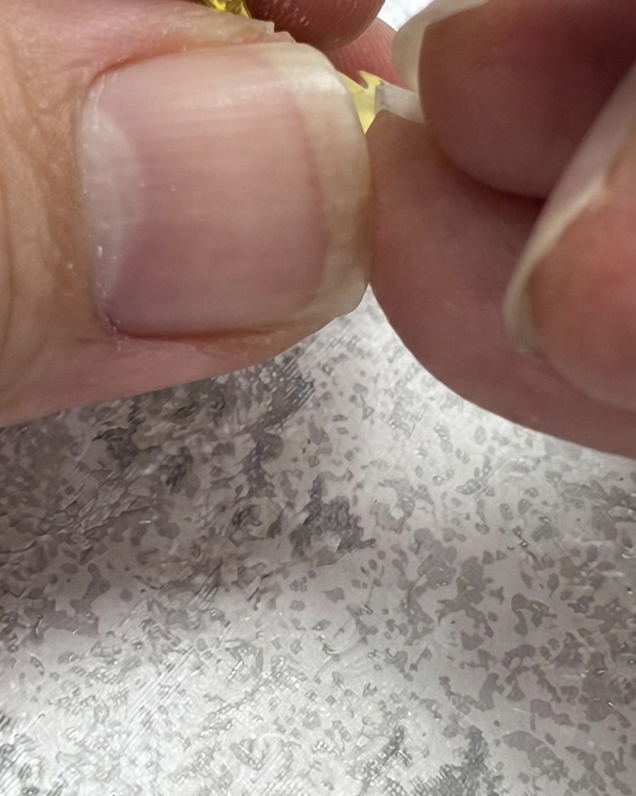 Un pincel para uñas dibujando un trazo verde hacia arriba para crear una forma de hoja junto a una margarita.