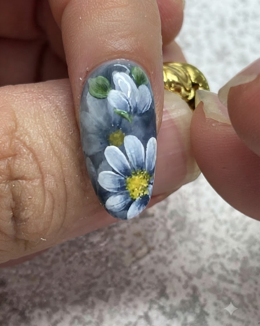 Un pincel fino añadiendo reflejos detallados sobre hojas verdes pintadas en una manicura de gel gris.