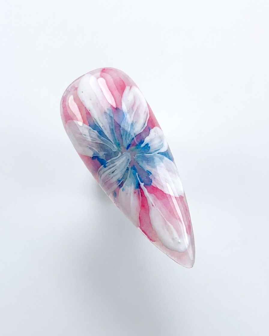 Una mano colocando una uña decorada bajo una lámpara de curado UV/LED rosa.